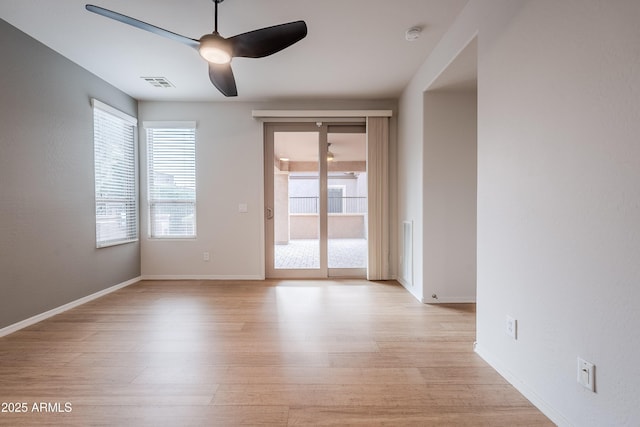 spare room featuring a ceiling fan, visible vents, a healthy amount of sunlight, and light wood-type flooring
