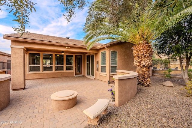 rear view of house featuring a patio, ceiling fan, stucco siding, and fence