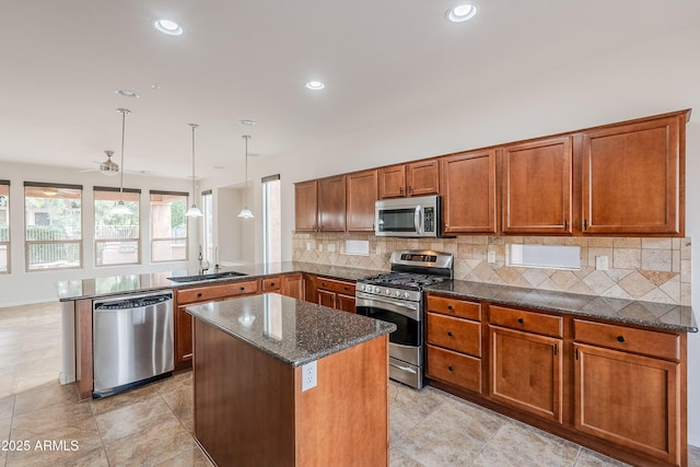 kitchen featuring brown cabinetry, a peninsula, a sink, appliances with stainless steel finishes, and backsplash