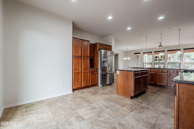 kitchen with ceiling fan, stainless steel refrigerator with ice dispenser, recessed lighting, a center island, and hanging light fixtures