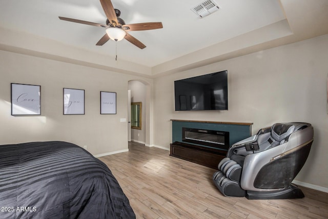 bedroom featuring a tray ceiling, ceiling fan, and light hardwood / wood-style floors