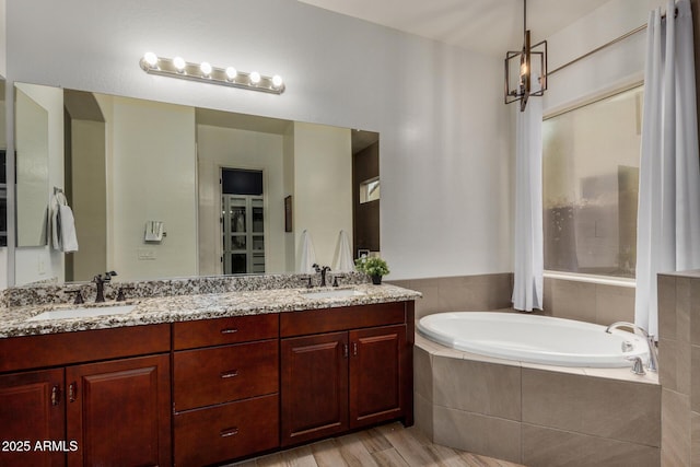 bathroom with vanity, wood-type flooring, and tiled tub