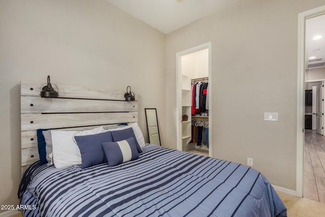 bedroom with light carpet, a spacious closet, and a closet