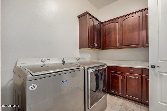 washroom with cabinets, separate washer and dryer, and light wood-type flooring