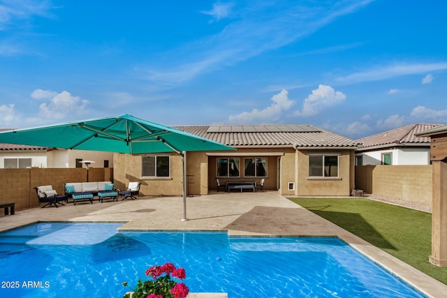 rear view of property with solar panels, a patio area, a fenced in pool, and an outdoor living space