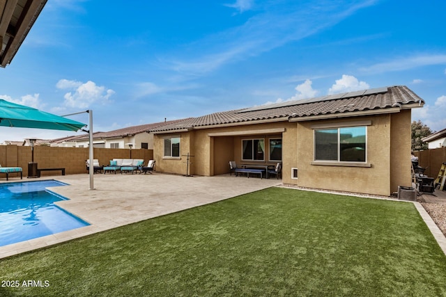 rear view of property with solar panels, a fenced in pool, an outdoor hangout area, and a yard