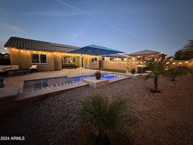 pool at dusk featuring outdoor lounge area, a jacuzzi, and a patio