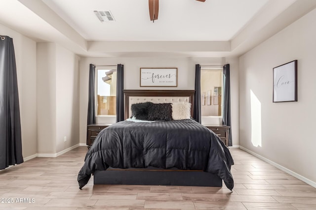 bedroom featuring a raised ceiling, ceiling fan, and light hardwood / wood-style floors