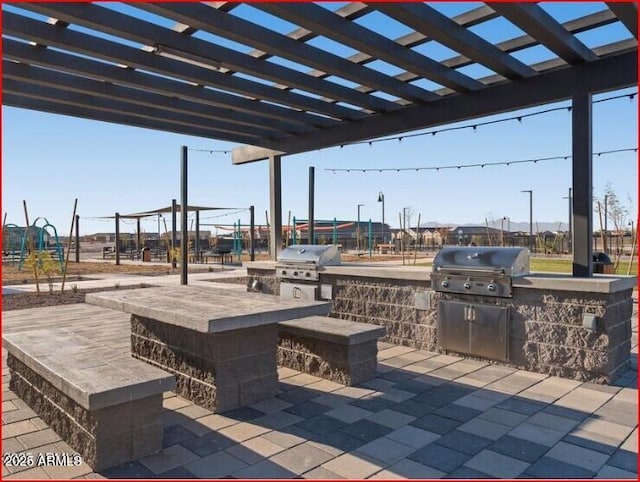 view of patio featuring grilling area, a pergola, and an outdoor kitchen