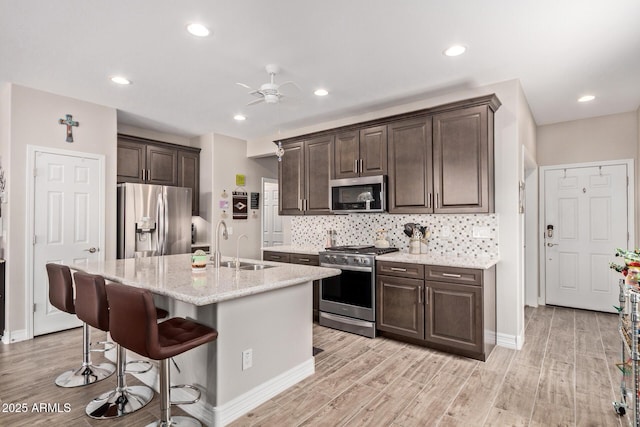 16756 S 181st Ln, Goodyear, AZ 85338 - kitchen with stainless steel appliances, dark brown cabinets, light stone counters, a breakfast bar, and a ceiling fan