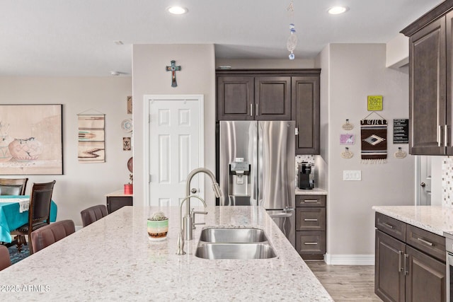 16756 S 181st Ln, Goodyear, AZ 85338 - kitchen featuring stainless steel fridge with ice dispenser, dark brown cabinetry, light wood-type flooring, light stone counters, and recessed lighting