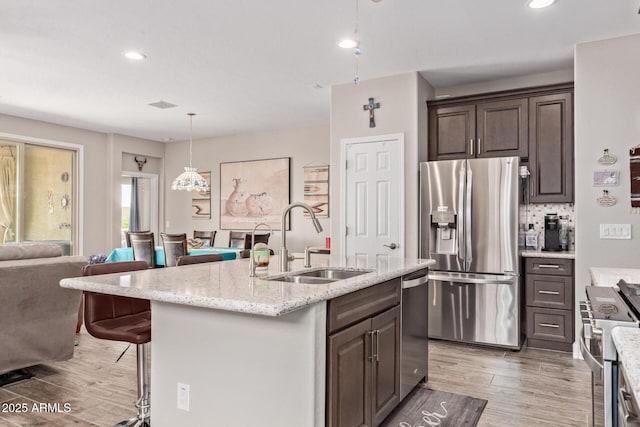 16756 S 181st Ln, Goodyear, AZ 85338 - kitchen with stainless steel appliances, light wood-type flooring, dark brown cabinets, light stone counters, and recessed lighting