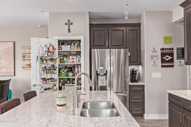16756 S 181st Ln, Goodyear, AZ 85338 - kitchen featuring dark brown cabinets, stainless steel fridge, light stone counters, and light wood-type flooring