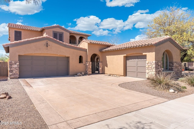 mediterranean / spanish-style house with a garage, stone siding, and stucco siding