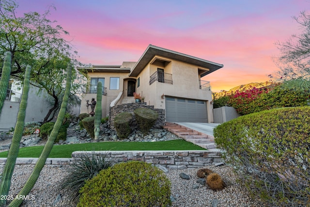 view of front of property featuring a garage, driveway, a balcony, and stucco siding