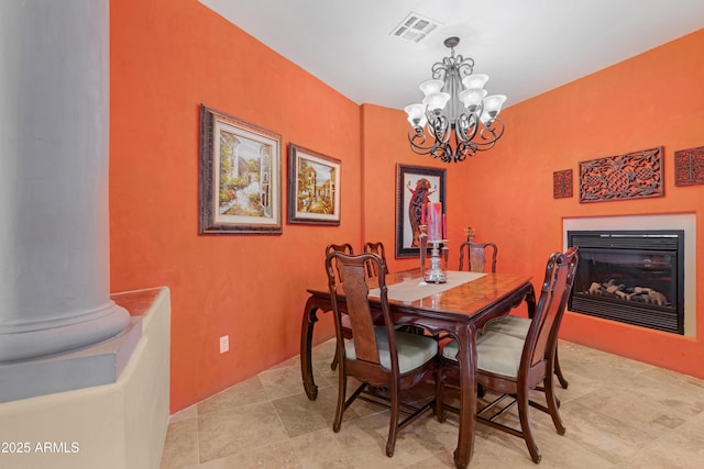 dining area featuring an inviting chandelier, visible vents, and a glass covered fireplace