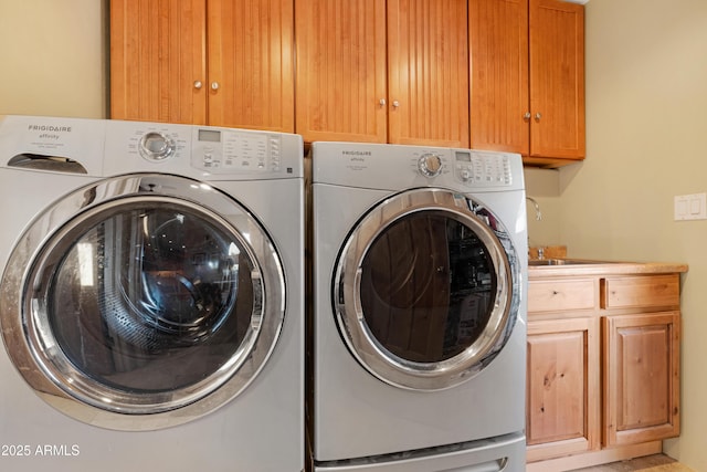 laundry room featuring washing machine and dryer, cabinets, and sink