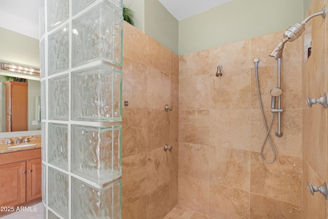 bathroom with a tile shower and vanity