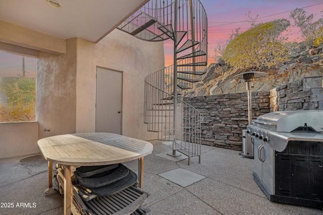 patio terrace at dusk featuring area for grilling