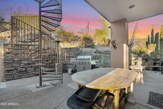 patio terrace at dusk featuring a grill