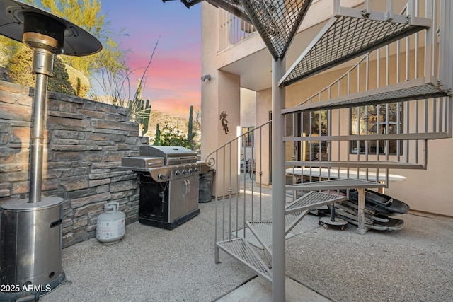 patio terrace at dusk featuring a grill