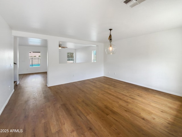 spare room with baseboards, dark wood-style floors, visible vents, and ceiling fan