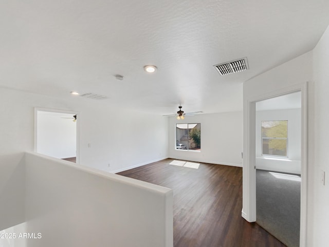 hall with dark wood-type flooring, an upstairs landing, baseboards, and visible vents