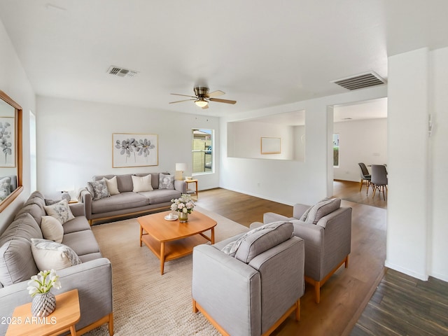 living area with ceiling fan, visible vents, baseboards, and wood finished floors