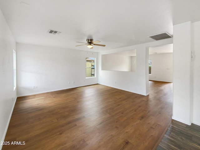 spare room featuring visible vents, baseboards, dark wood-type flooring, and a ceiling fan