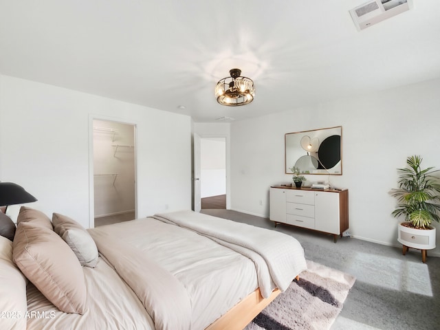 carpeted bedroom featuring visible vents, baseboards, a walk in closet, and an inviting chandelier