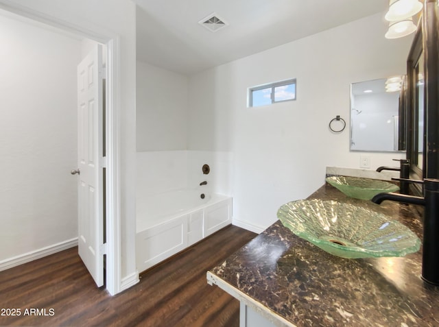 bathroom featuring visible vents, baseboards, a garden tub, and wood finished floors