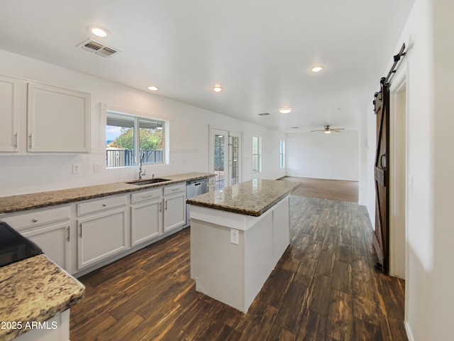 kitchen with a sink, visible vents, dark wood-type flooring, and a center island