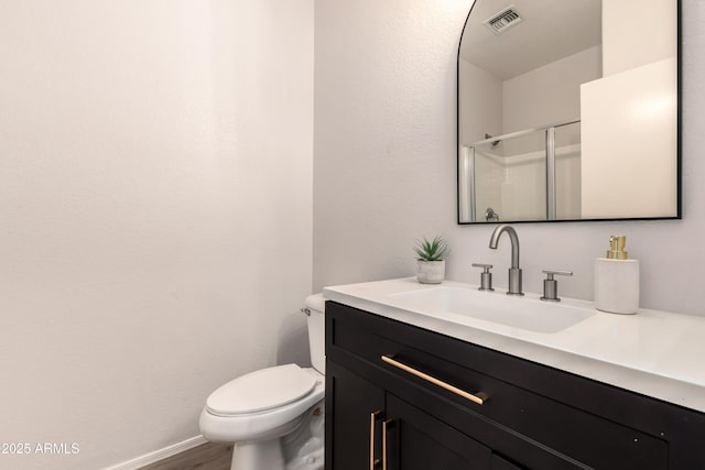 bathroom featuring vanity, toilet, a shower with shower door, and wood-type flooring