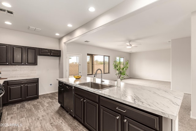 kitchen featuring dishwasher, sink, backsplash, ceiling fan, and a center island with sink