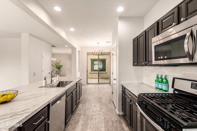 kitchen featuring sink, light stone counters, tasteful backsplash, hanging light fixtures, and stainless steel appliances