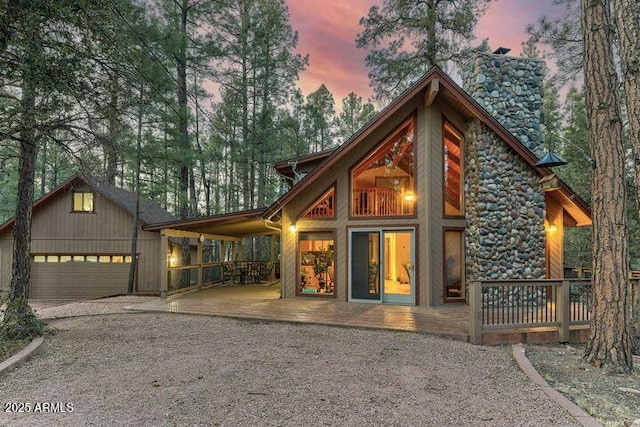 back of property at dusk with stone siding, driveway, and an attached garage