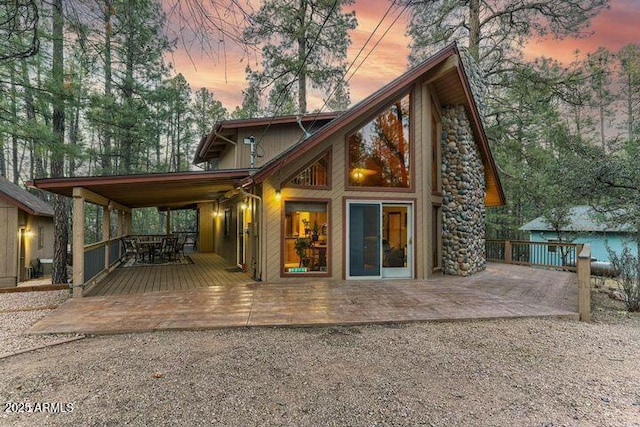 back of house at dusk with a patio area and a wooden deck