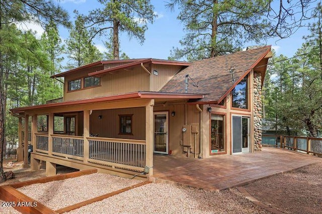 view of front facade with a patio area and roof with shingles