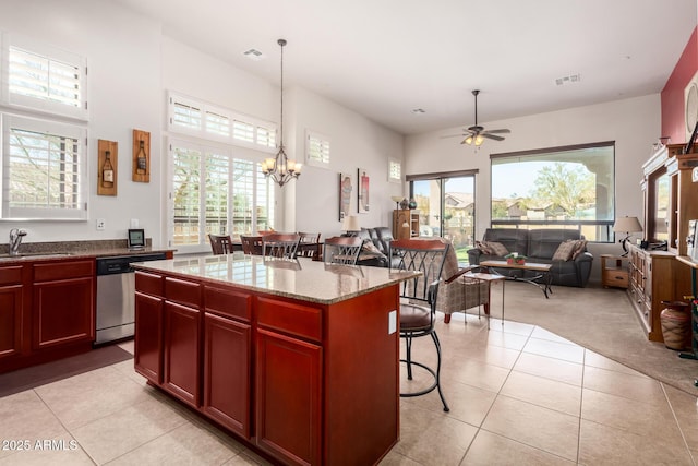 kitchen featuring a healthy amount of sunlight, visible vents, a breakfast bar, dark brown cabinets, and dishwasher