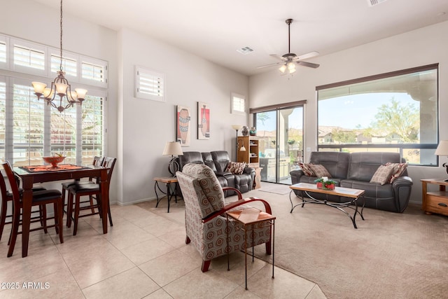 living area with light tile patterned floors, visible vents, a healthy amount of sunlight, and ceiling fan with notable chandelier