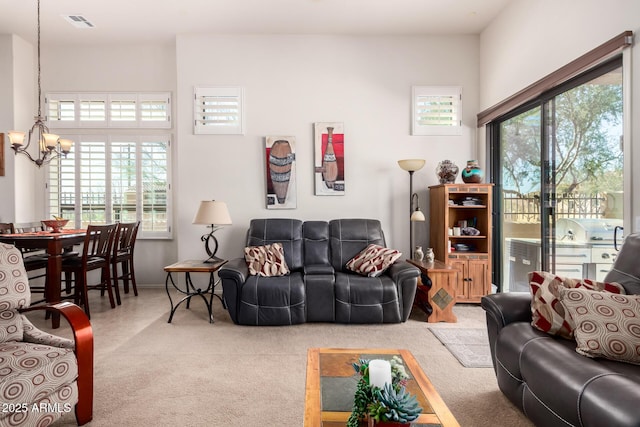 carpeted living room with a wealth of natural light, visible vents, and a notable chandelier