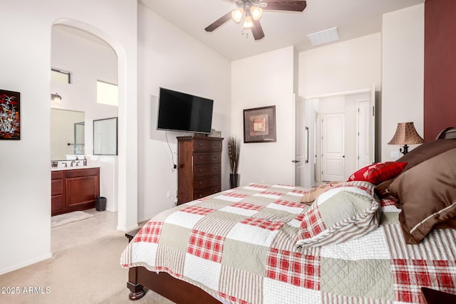 bedroom featuring visible vents, light carpet, a sink, connected bathroom, and baseboards