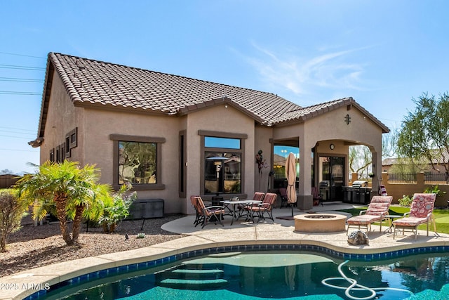 back of property featuring stucco siding, a patio area, a fire pit, a fenced in pool, and a tiled roof