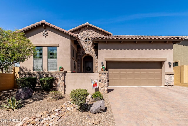 mediterranean / spanish house with fence, stucco siding, decorative driveway, a garage, and stone siding