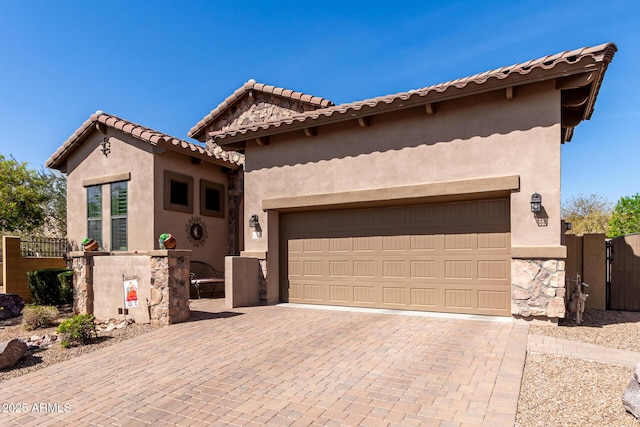 view of front of house with fence, stucco siding, decorative driveway, an attached garage, and a gate