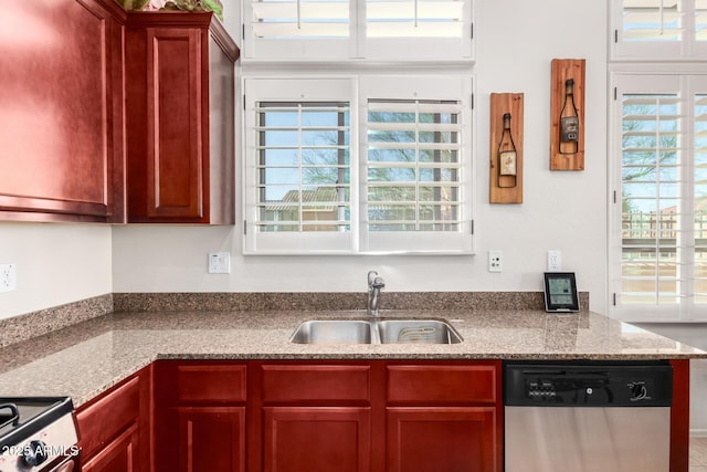 kitchen with a sink, reddish brown cabinets, stainless steel dishwasher, and a healthy amount of sunlight