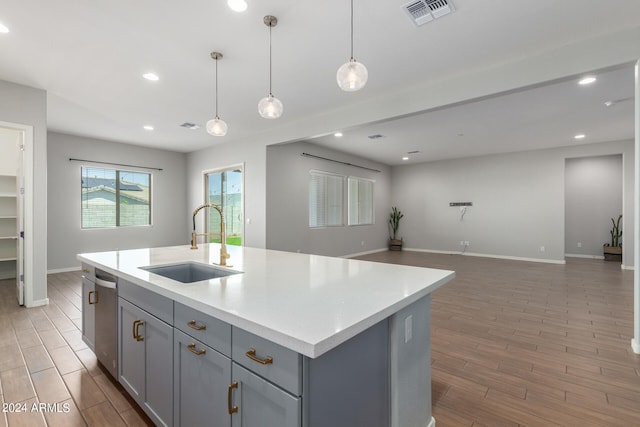 kitchen featuring an island with sink, decorative light fixtures, sink, and stainless steel dishwasher