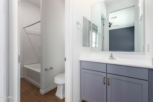 full bathroom featuring hardwood / wood-style flooring, vanity, tub / shower combination, ceiling fan, and toilet