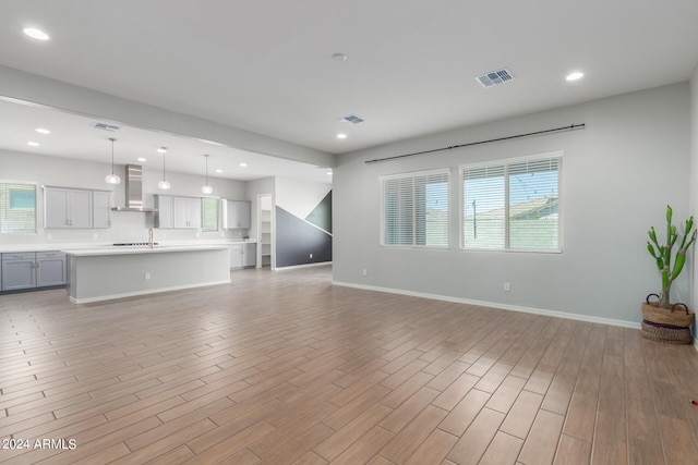 unfurnished living room with sink and light wood-type flooring