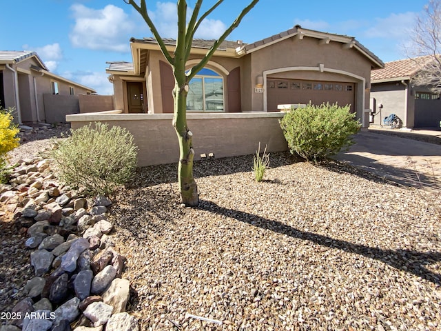 view of front of home with a fenced front yard, stucco siding, an attached garage, and driveway